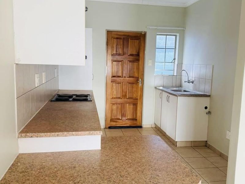 A functional kitchen featuring laminate countertops, a built-in electric hob, tiled splashbacks, and ample cabinetry, providing a clean and practical workspace.