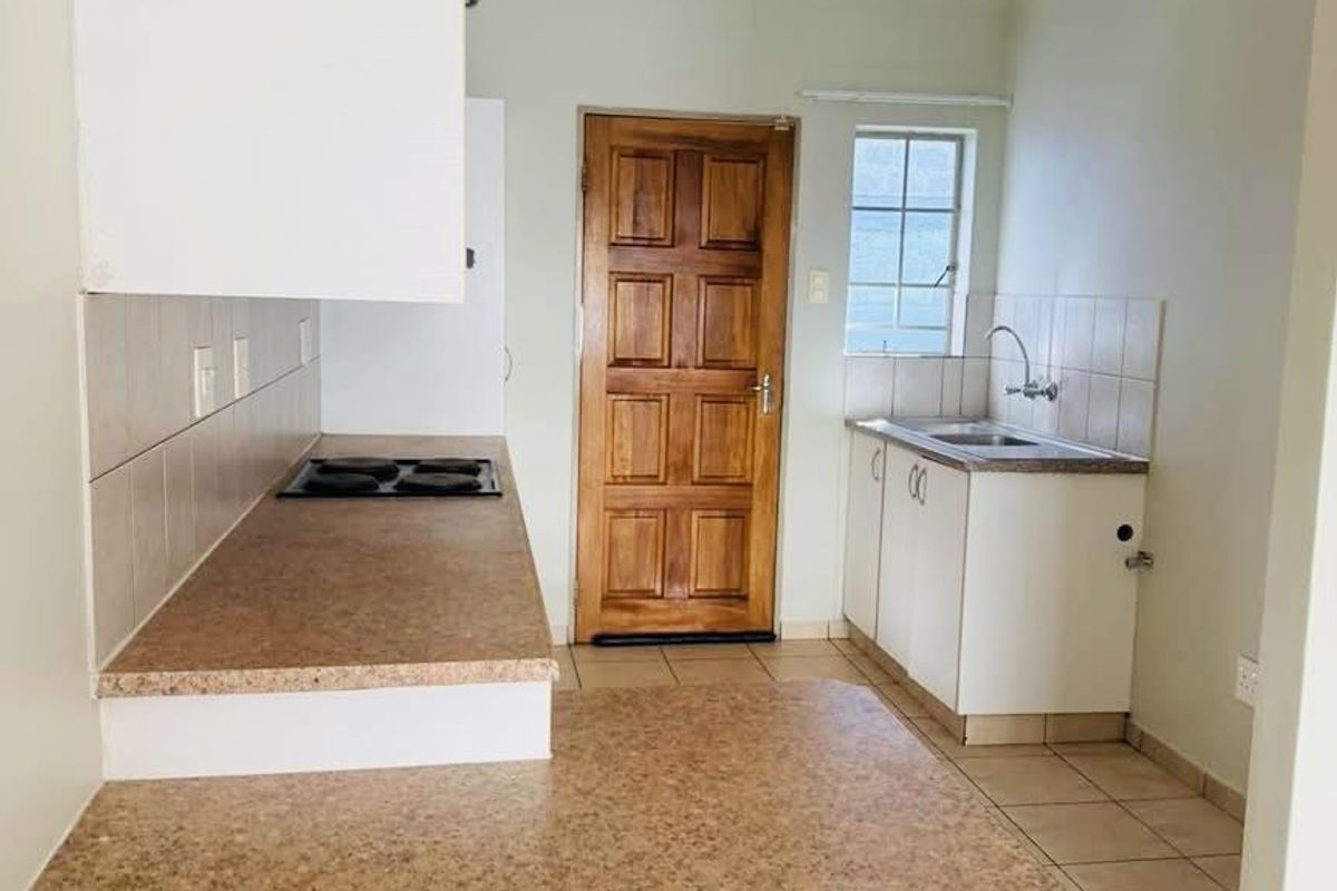 A functional kitchen featuring laminate countertops, a built-in electric hob, tiled splashbacks, and ample cabinetry, providing a clean and practical workspace.