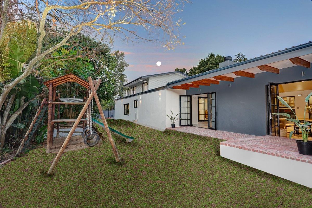 Rear view of the property featuring a brick patio, exposed timber rafters, and french doors leading into the home, set against a landscaped garden.