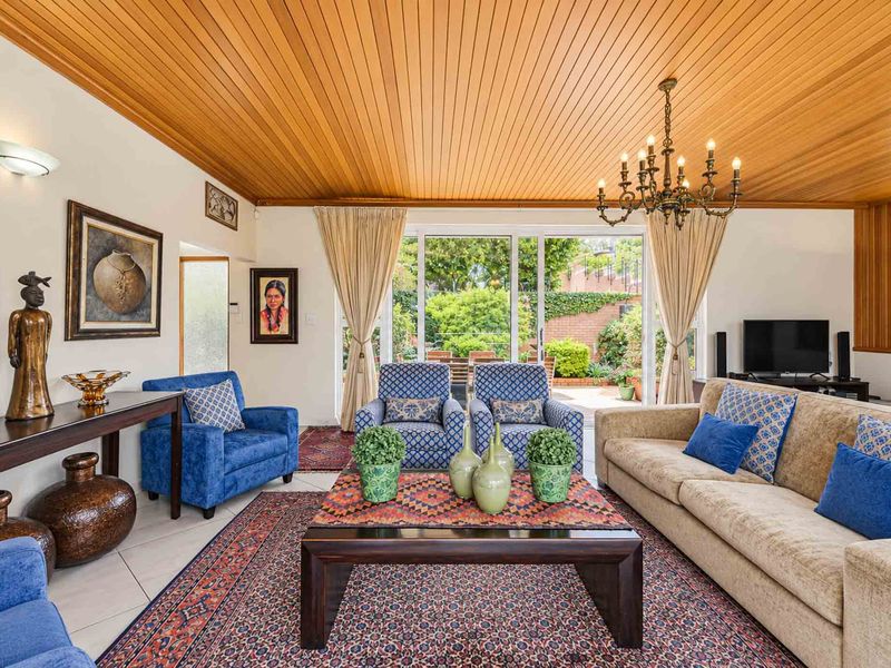 Spacious living room featuring a warm timber-clad ceiling, tiled flooring, and large sliding glass doors providing direct access to the outdoor patio area.