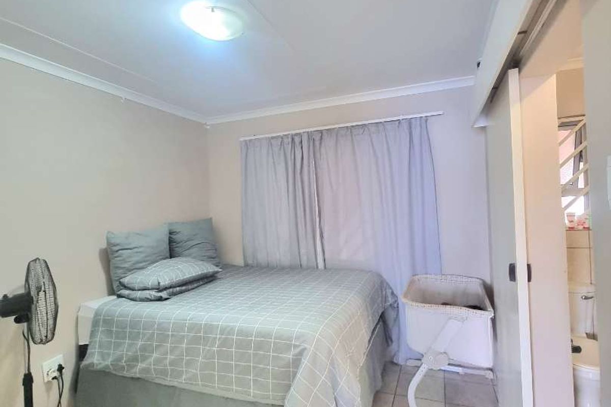 A bedroom featuring tiled flooring and an adjoining en-suite bathroom accessed via a sliding door.