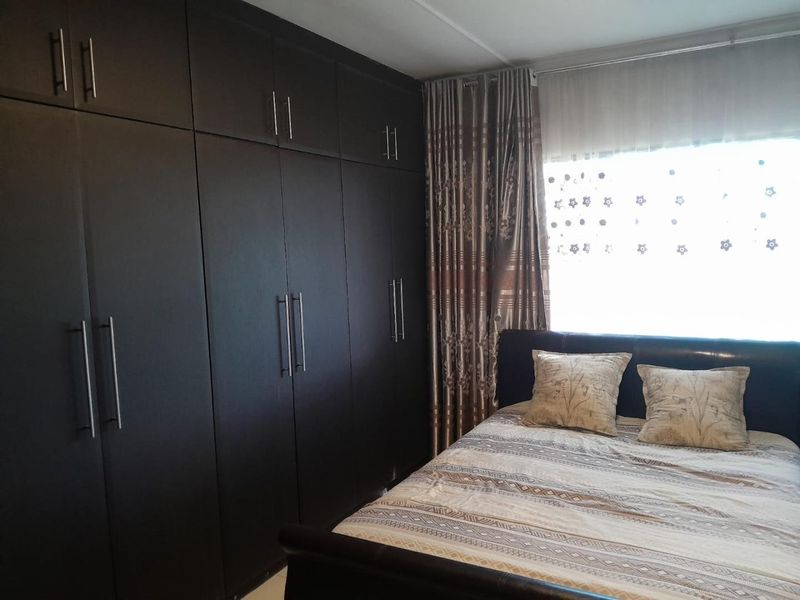 A bedroom featuring extensive floor-to-ceiling dark wood built-in cupboards providing ample storage space.