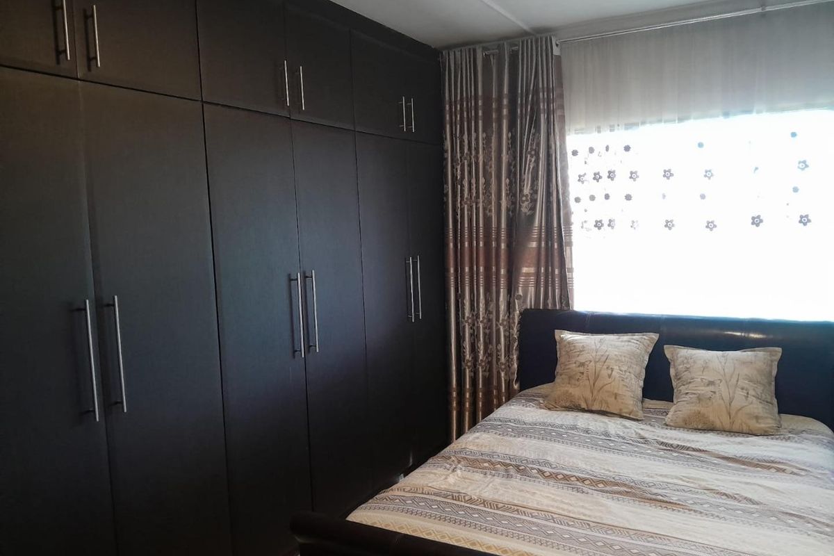 A bedroom featuring extensive floor-to-ceiling dark wood built-in cupboards providing ample storage space.
