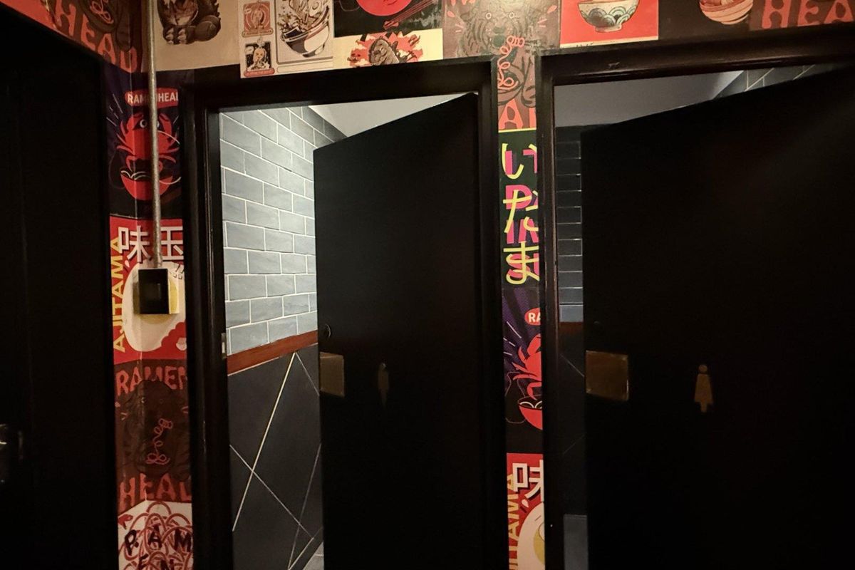 A commercial restroom entrance area featuring tiled walls and distinct signage on the door frames.