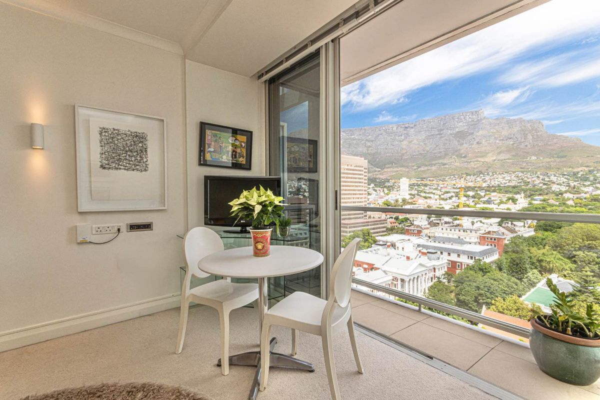 A bright living area featuring large sliding glass doors that open to a balcony with expansive city and mountain views.