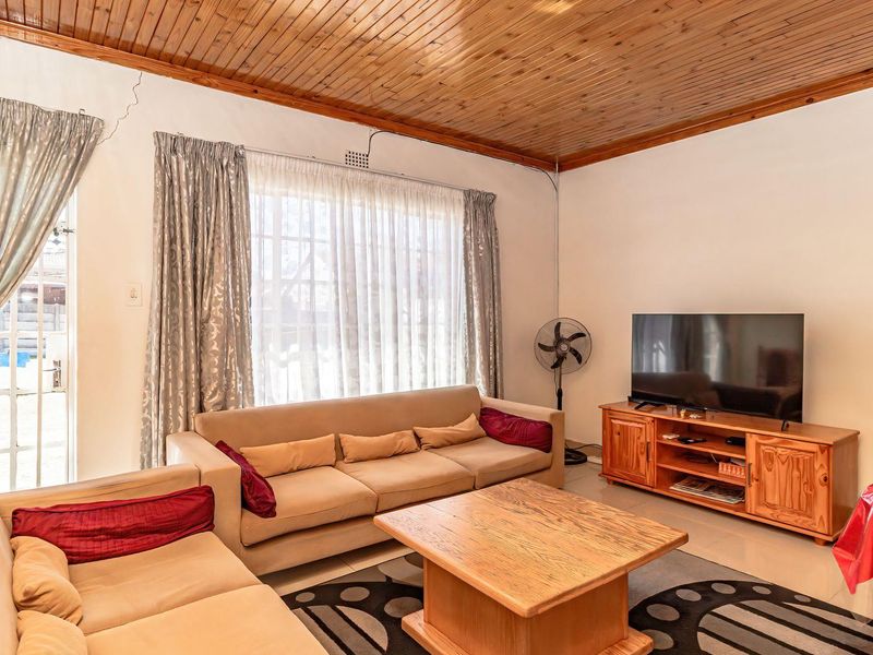 A living room featuring tiled flooring and a timber tongue and groove ceiling, with access to the exterior via a sliding glass door.
