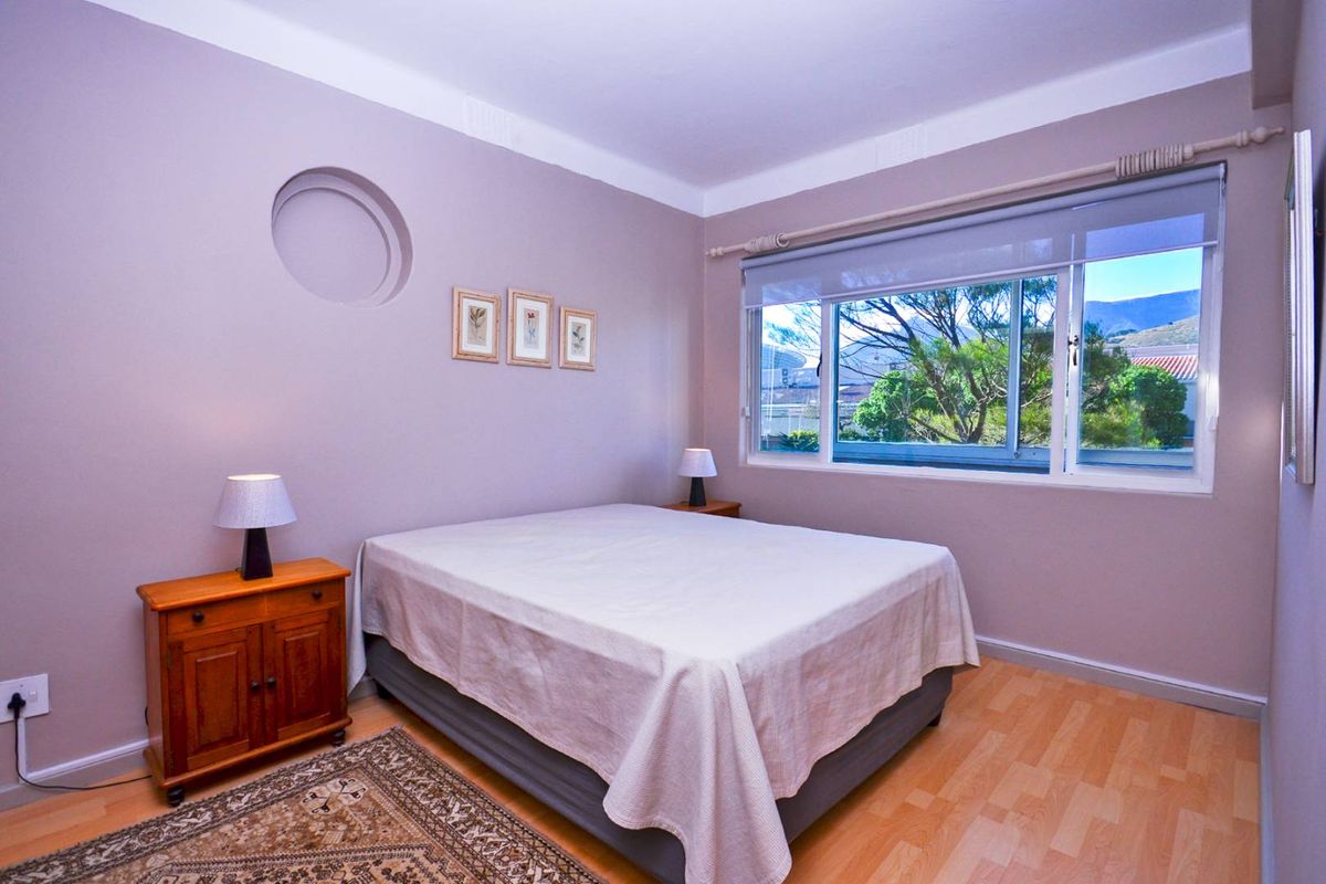 A well-maintained bedroom featuring laminate flooring, a unique circular wall niche, and a large sliding window providing natural light and exterior views.