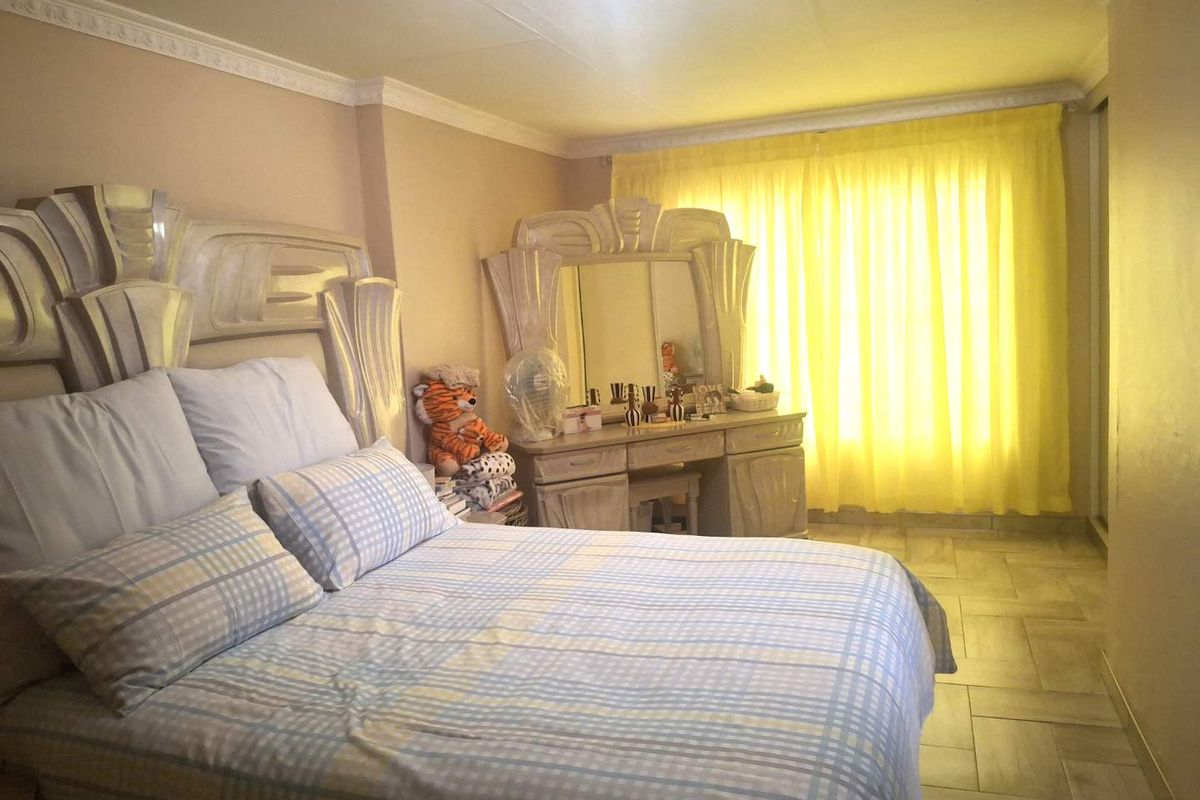 A bedroom featuring tiled flooring, built-in wardrobe storage, and decorative ceiling cornicing, providing a functional and well-lit sleeping space.