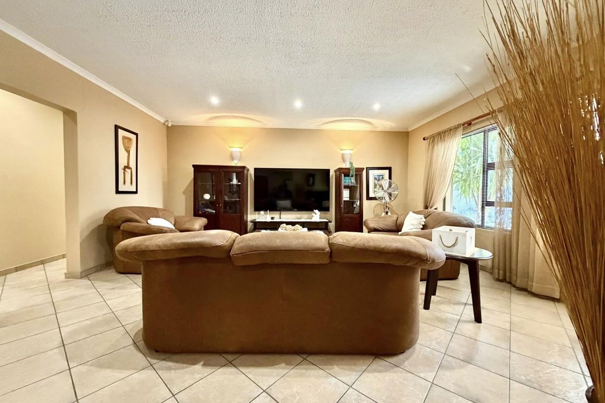 A spacious living room featuring neutral wall tones, tiled flooring, and recessed downlighting, creating a comfortable and functional family living area.