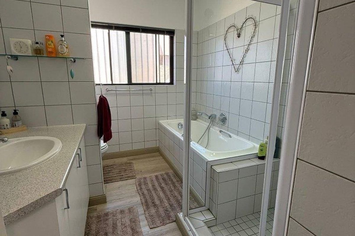 A functional bathroom featuring a built-in bathtub, a separate glass-enclosed shower, and a vanity with a basin.