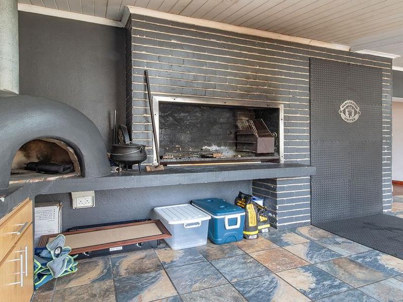 Covered outdoor entertainment area featuring a built-in braai and pizza oven with tiled flooring.