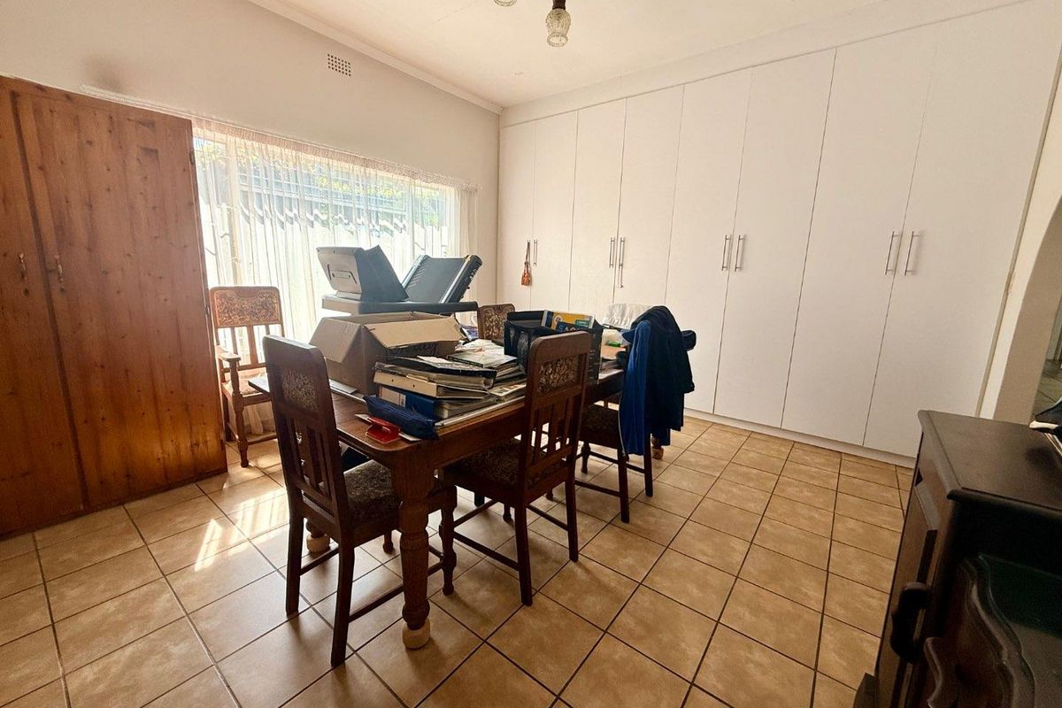A functional bedroom featuring extensive floor-to-ceiling built-in cabinetry, tiled flooring, and large windows allowing for natural light.