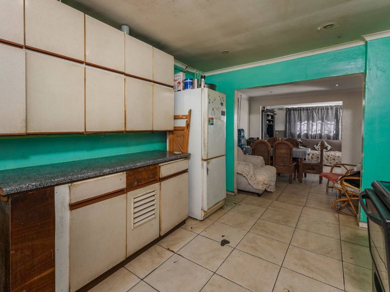 A dated kitchen featuring laminate cabinetry and tiled flooring, requiring cosmetic updates and modernization to improve its overall appeal and functionality.