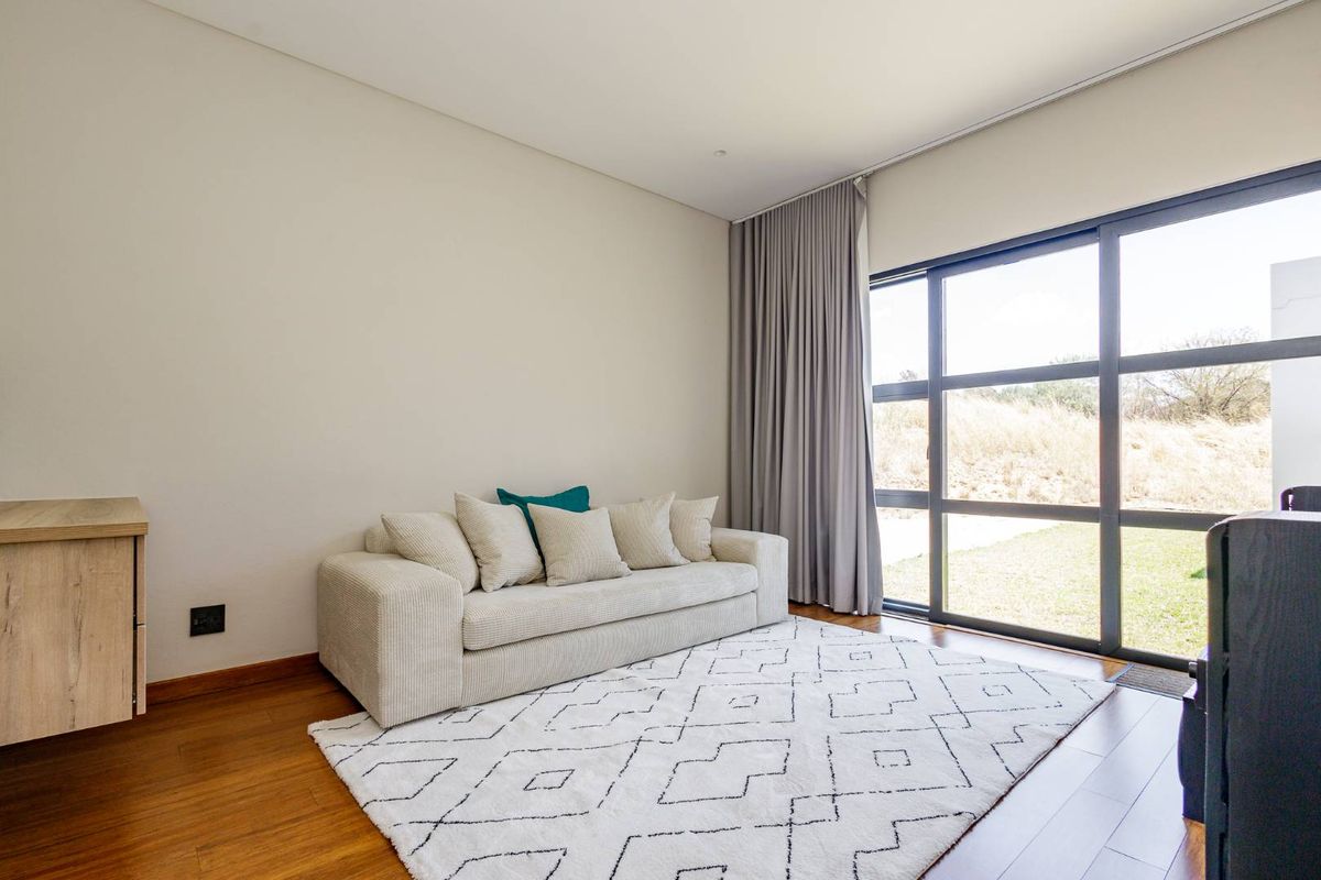 A bright living room featuring warm timber flooring, neutral walls, and large sliding glass doors that provide ample natural light and garden access.