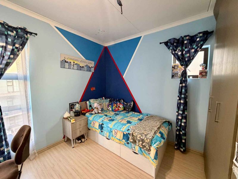 A bedroom featuring laminate flooring, a built-in wardrobe, and decorative wall paint.
