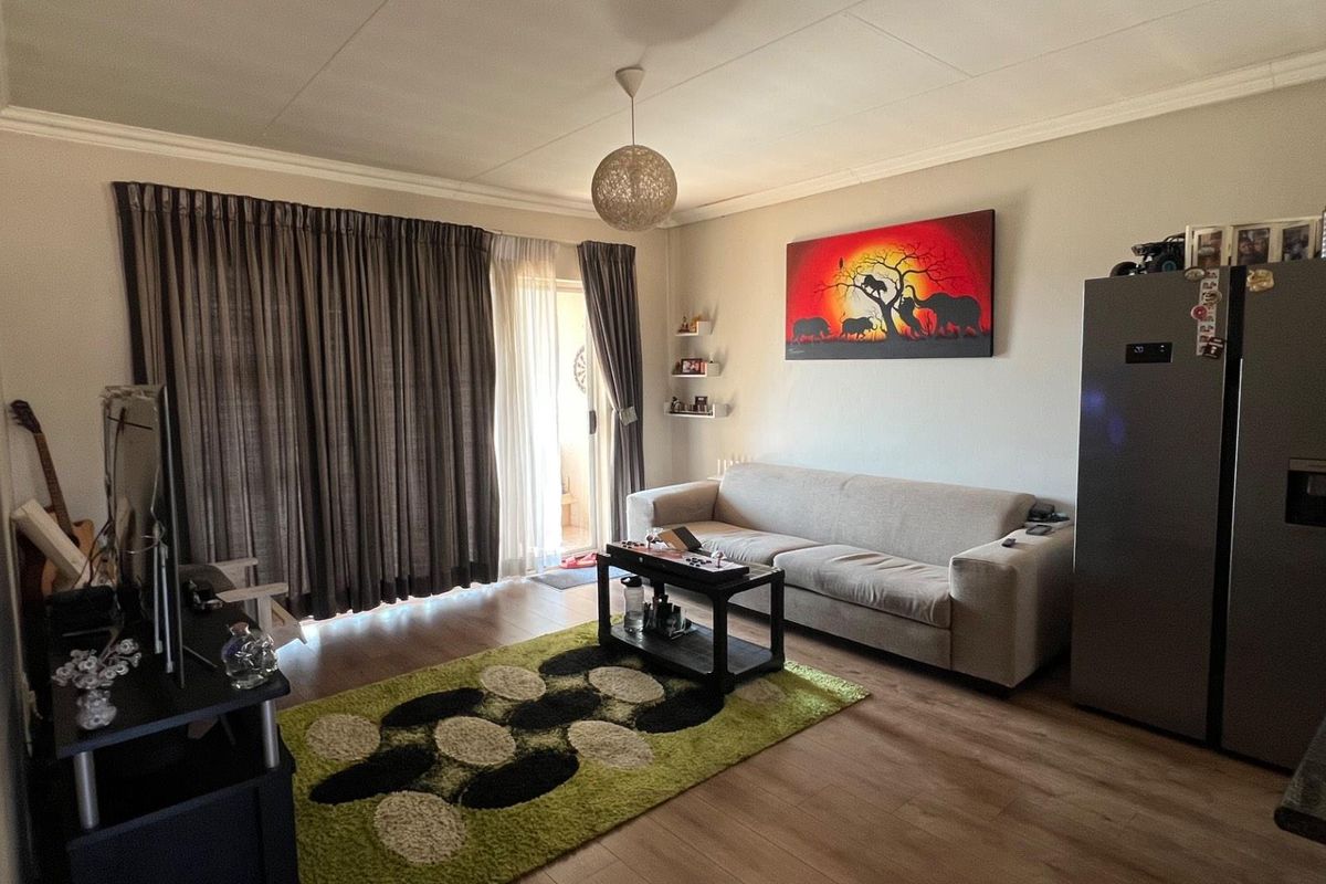 A comfortable living room featuring laminate flooring and a sliding glass door providing access to an outdoor area.