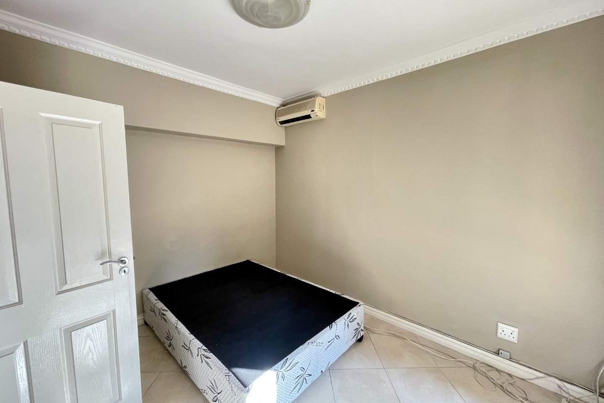 A bedroom featuring tiled flooring, crown molding, and a wall-mounted air conditioning unit.