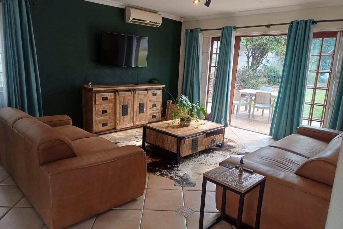 A comfortable living room featuring tiled flooring, a split-system air conditioner, and large sliding glass doors providing direct access to the outdoor patio area.