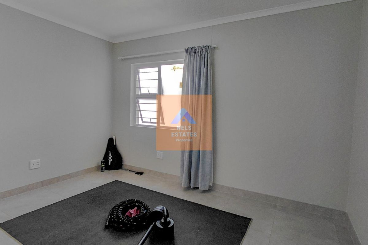 A clean, neutral-toned bedroom featuring tiled flooring and an aluminium window frame, offering a blank canvas for personalization.