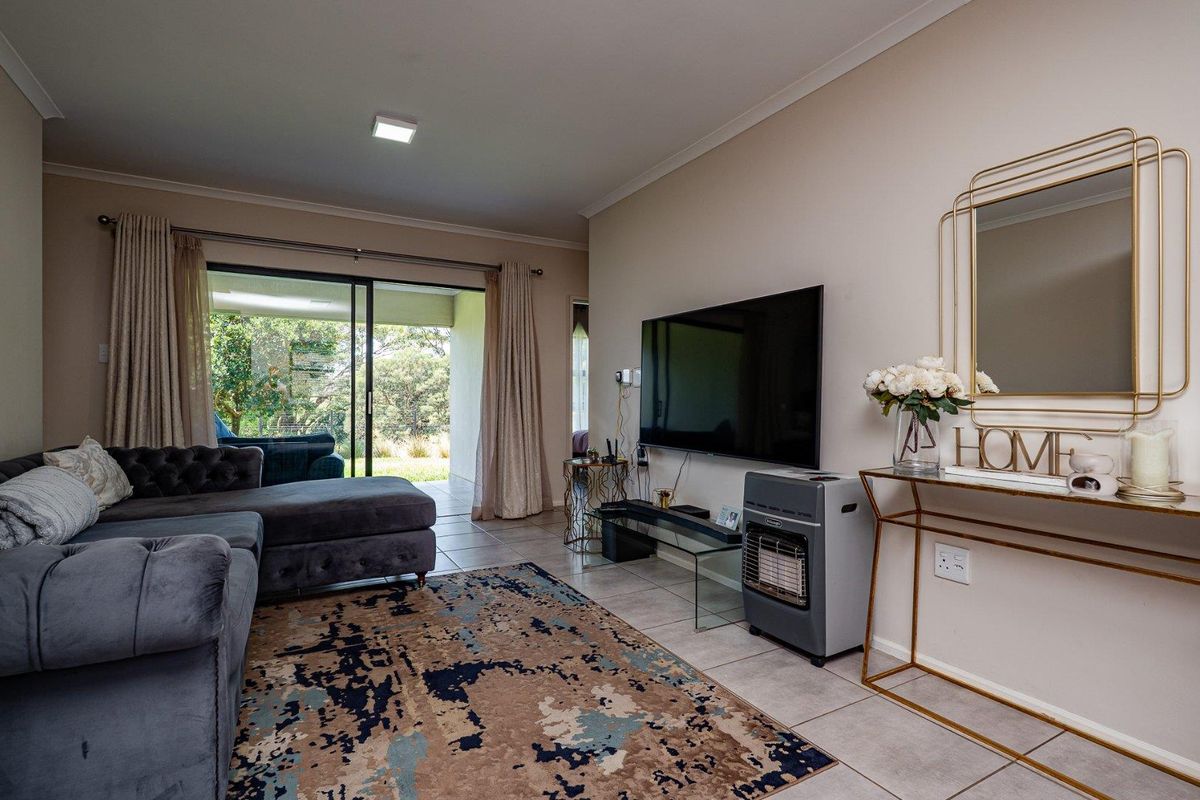 A comfortable living room featuring tiled flooring, sliding glass doors leading to a patio, and a wall-mounted television setup.