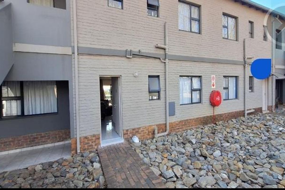 Rear exterior view of a multi-story apartment building featuring brick masonry, paved walkways, and functional fire safety equipment.