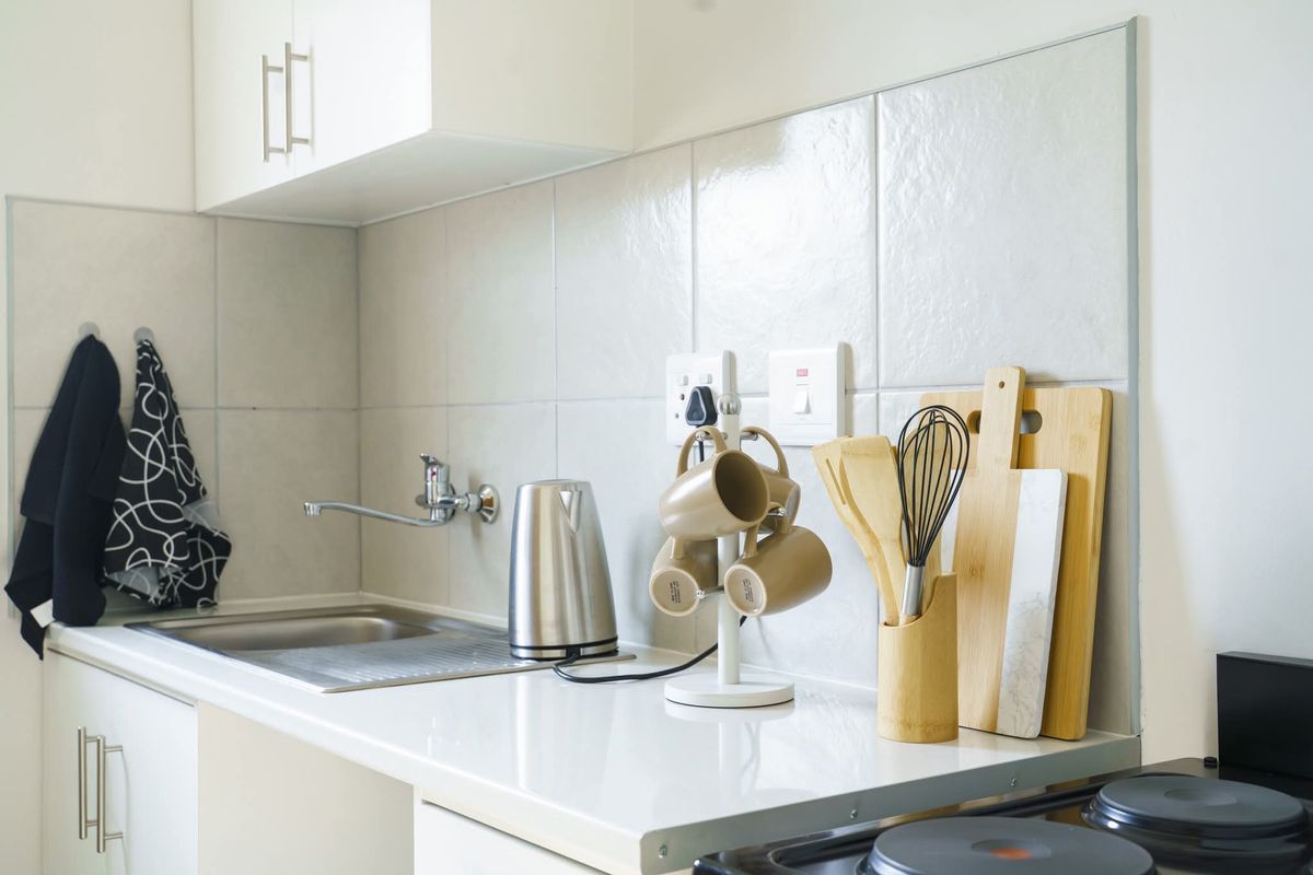 A clean and functional kitchen area featuring a stainless steel sink, tiled backsplash, and ample counter space with built-in cabinetry.