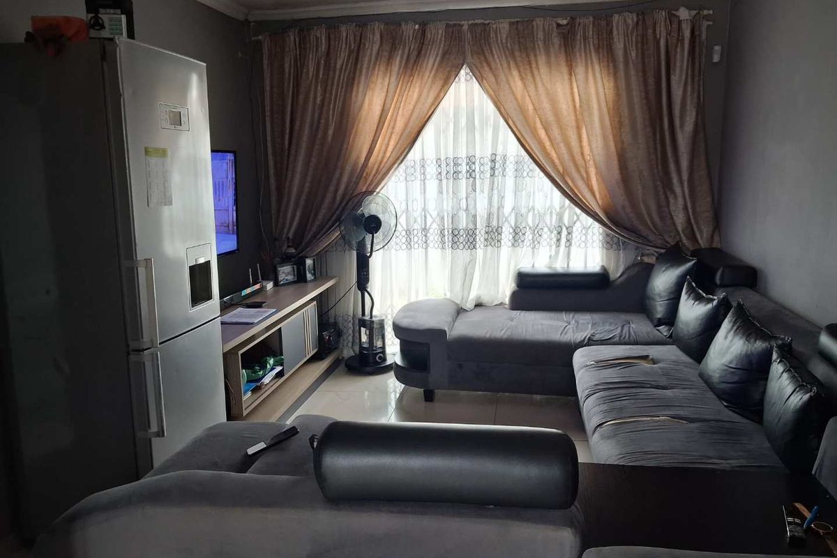 A living room featuring tiled flooring and large window with curtains, providing a functional space for relaxation.