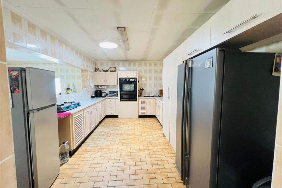 A functional kitchen featuring built-in cabinetry, a wall-mounted oven, and tiled flooring, offering a practical layout for daily meal preparation.