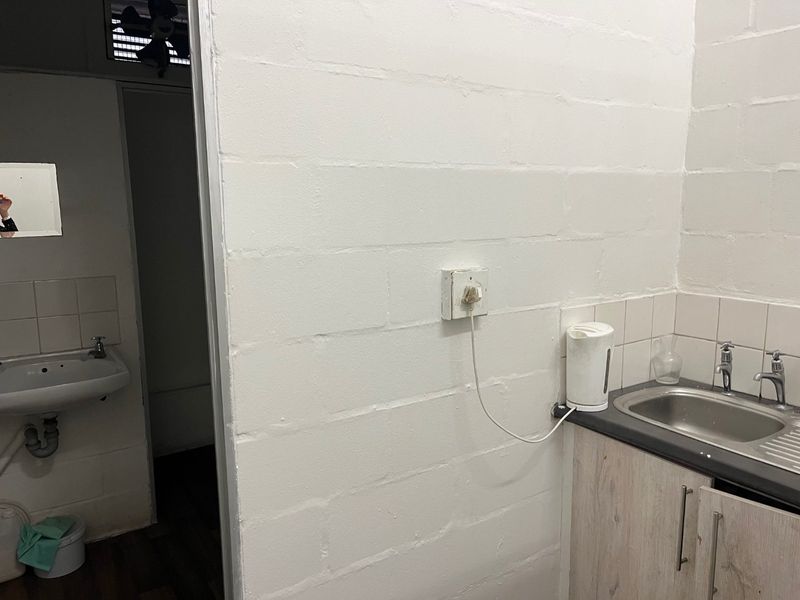 A functional scullery or utility area featuring a stainless steel sink, built-in cabinetry, and tiled splashback, providing essential prep and wash-up space.