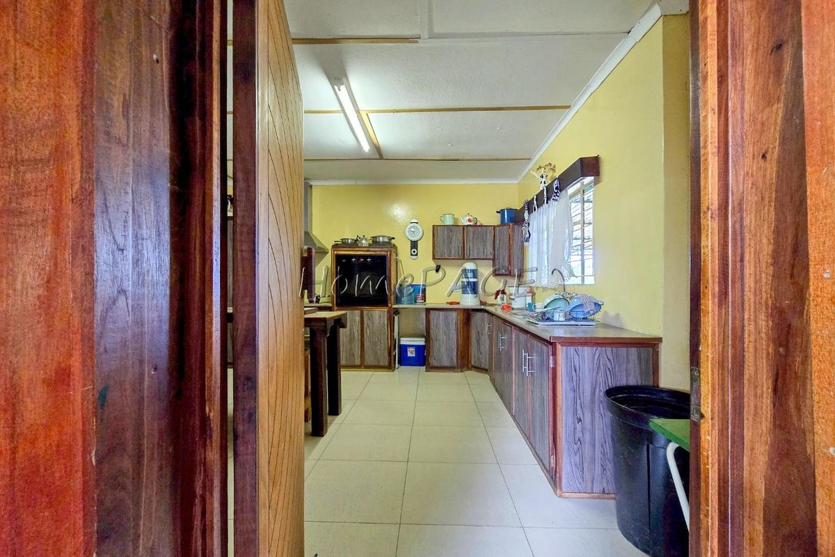 A functional kitchen featuring wood-look cabinetry, tiled flooring, and a built-in oven, viewed from the doorway.