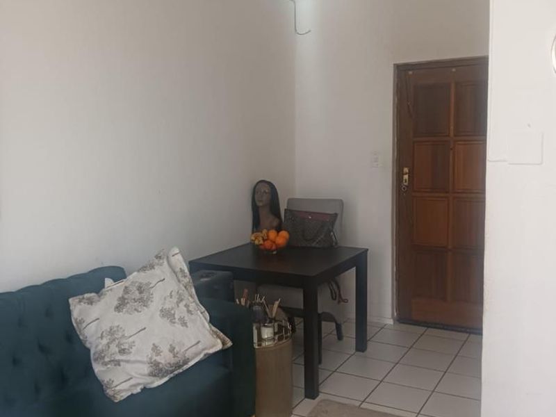 A living area featuring tiled flooring and a traditional timber entrance door, requiring cosmetic updates to improve the overall aesthetic and finish.