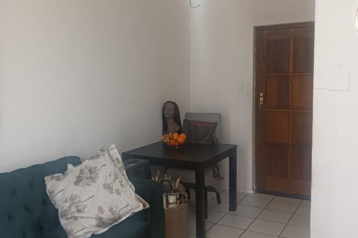 A living area featuring tiled flooring and a traditional timber entrance door, requiring cosmetic updates to improve the overall aesthetic and finish.