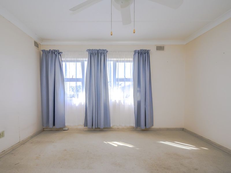 An empty bedroom featuring a ceiling fan and carpeted flooring, ready for renovation or staging.