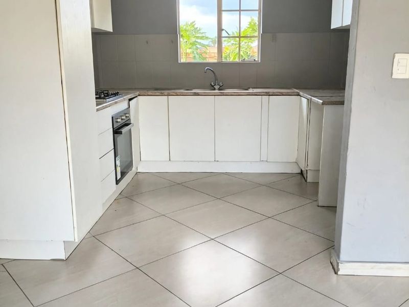A functional kitchen featuring white built-in cabinetry, laminate countertops, a built-in oven, gas hob, and neutral tiled flooring.