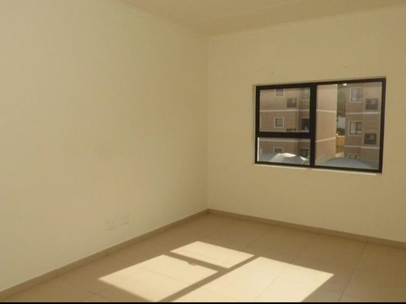 A clean, empty bedroom featuring neutral tiled flooring and a modern aluminium-framed window, providing a blank canvas for personalization.