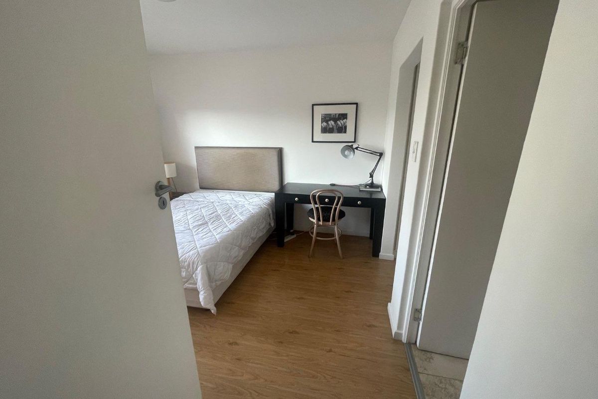 A functional bedroom featuring light wood-look laminate flooring and neutral walls, providing a clean and simple living space.