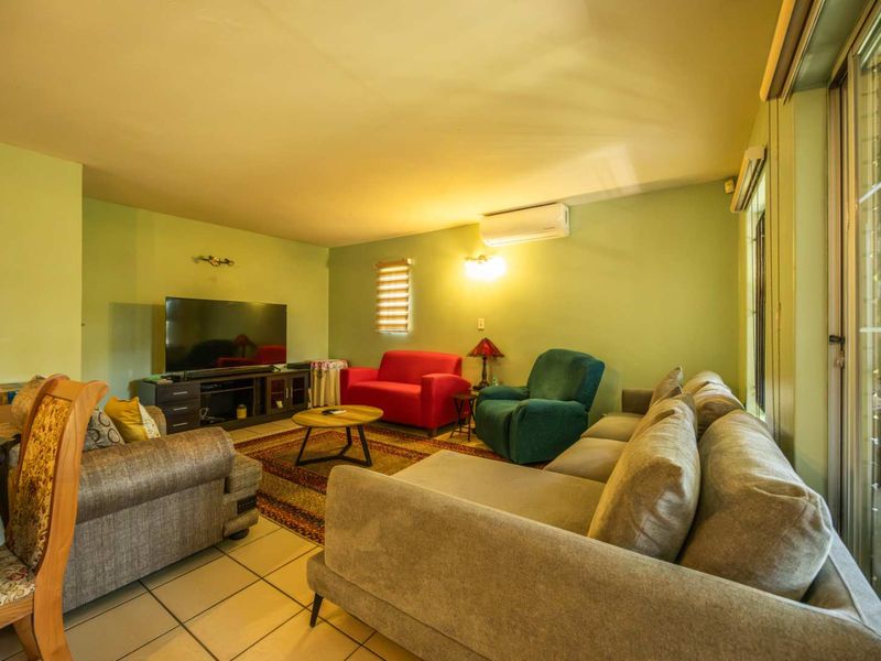 A spacious living room featuring tiled flooring, a split-system air conditioner, and large sliding glass doors that provide access to the outdoor area.