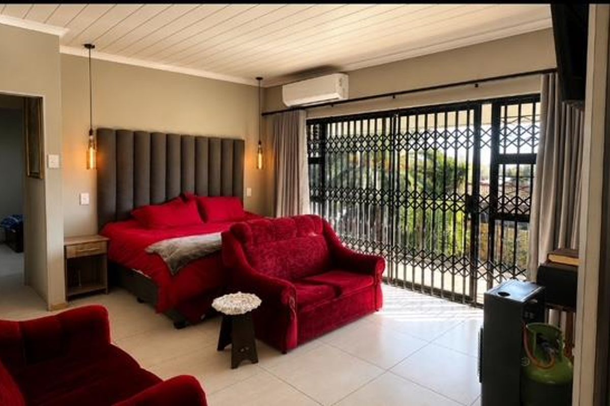 Spacious bedroom featuring tiled flooring, a built-in headboard, split-system air conditioning, and direct access to an outdoor area through a secure metal gate.