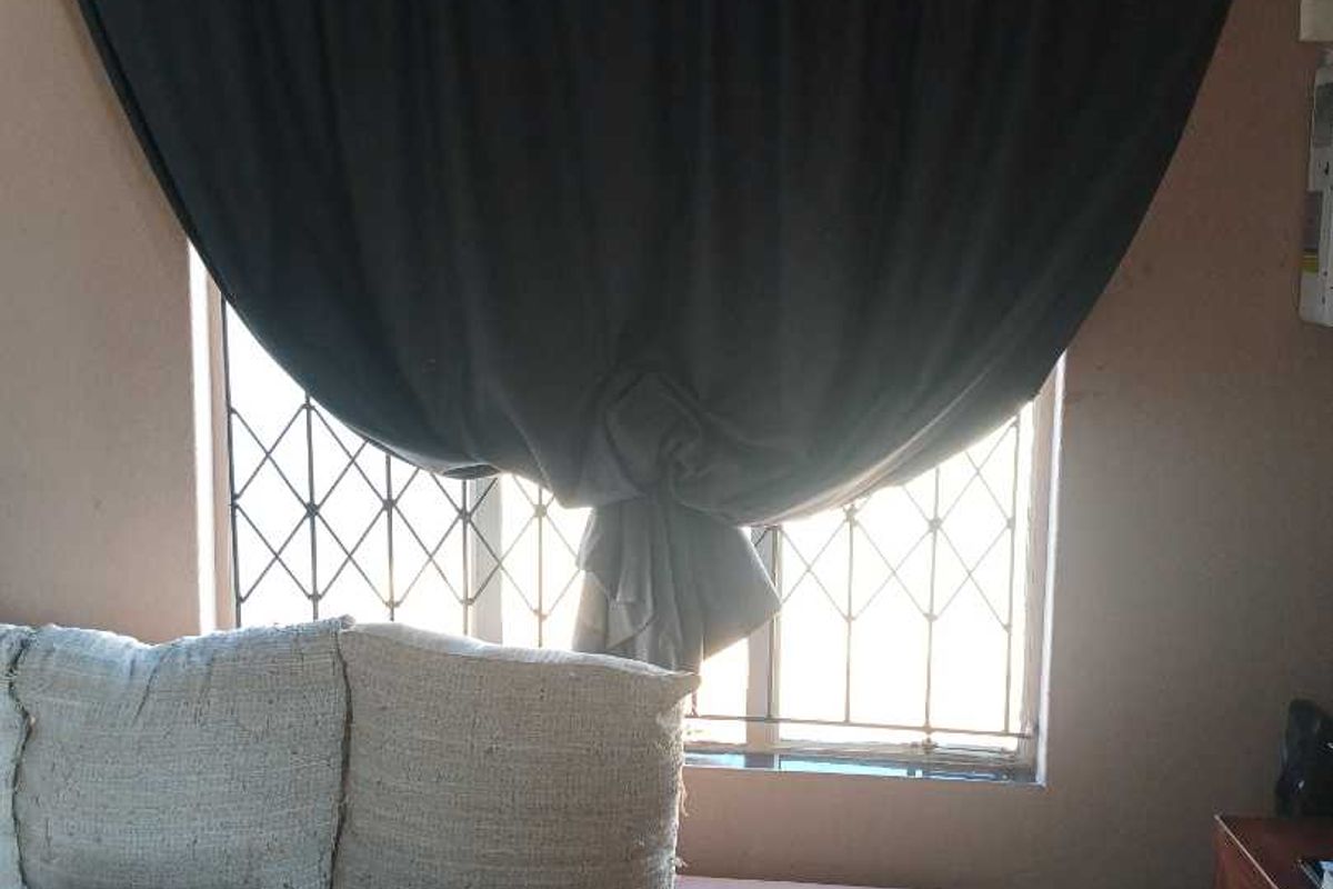 A bedroom interior featuring a window fitted with security burglar bars.