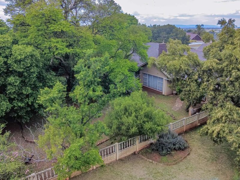 Aerial view of the property showcasing the mature garden, tiled roof structure, and perimeter boundary walling.