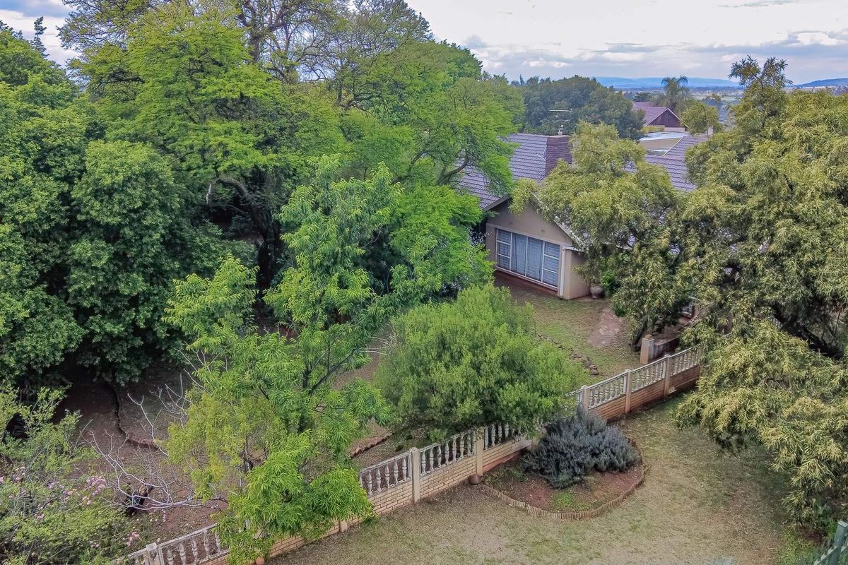 Aerial view of the property showcasing the mature garden, tiled roof structure, and perimeter boundary walling.