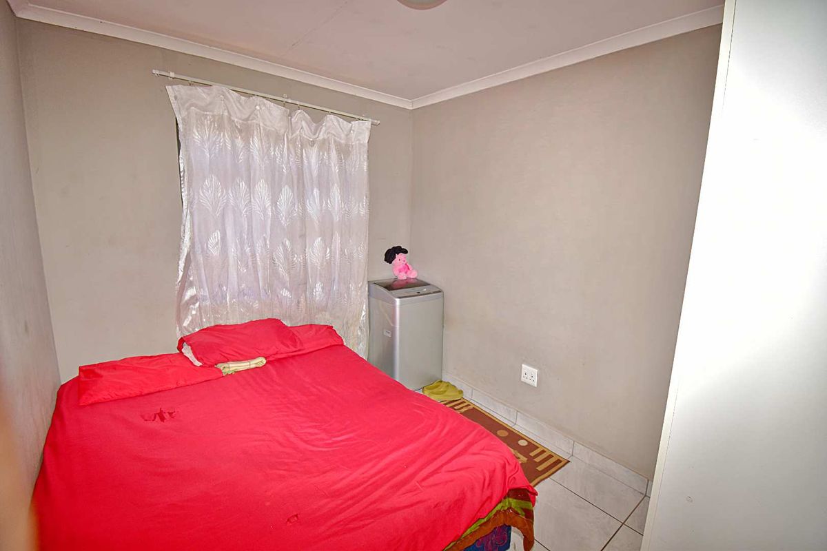 A compact bedroom featuring tiled flooring, neutral wall paint, and a built-in wardrobe space.