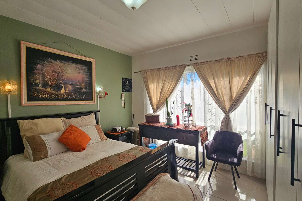 A well-lit bedroom featuring built-in floor-to-ceiling wardrobes, tiled flooring, and large windows that allow for ample natural light.