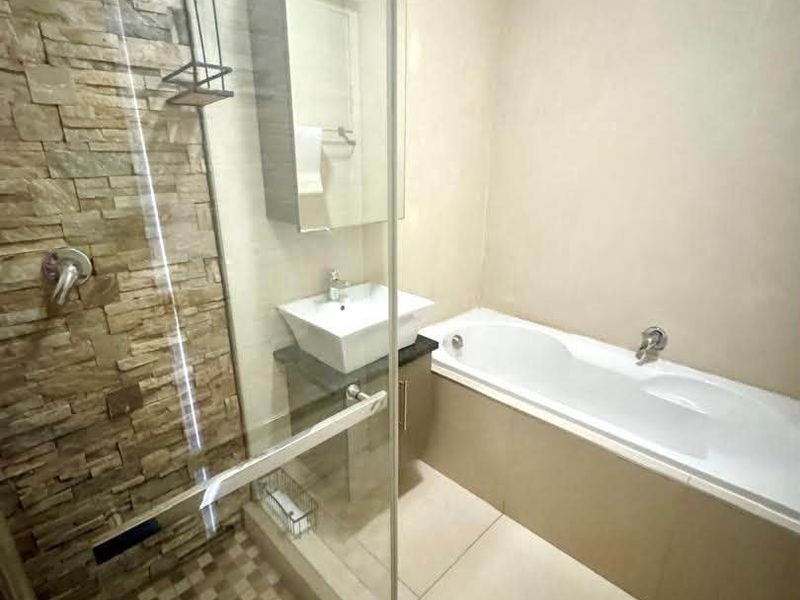 Modern bathroom featuring a glass-enclosed shower with stone accent wall, a built-in bathtub, and a vanity with a vessel sink.
