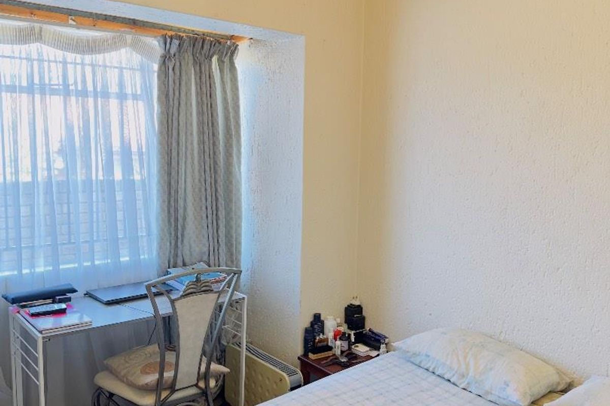 A functional bedroom featuring a recessed window area, crown molding, and neutral wall finishes, suitable for a comfortable sleeping or study space.