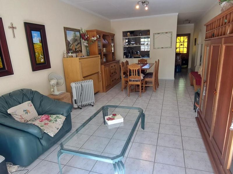 Open plan living and dining area featuring tiled flooring and a kitchen serving hatch, providing a functional and connected layout.