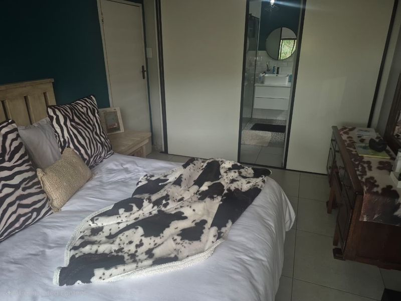 A bedroom featuring built-in cupboards and direct access to an en-suite bathroom with tiled flooring throughout.