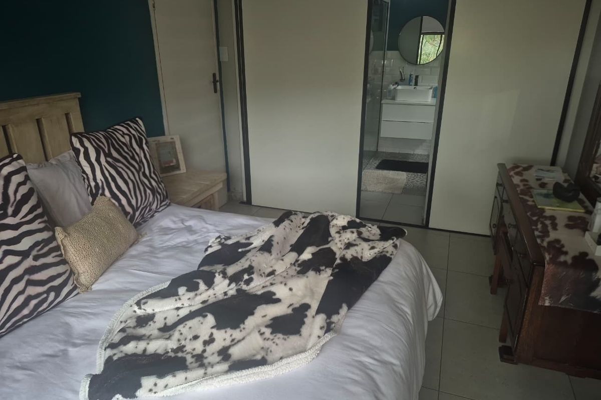 A bedroom featuring built-in cupboards and direct access to an en-suite bathroom with tiled flooring throughout.