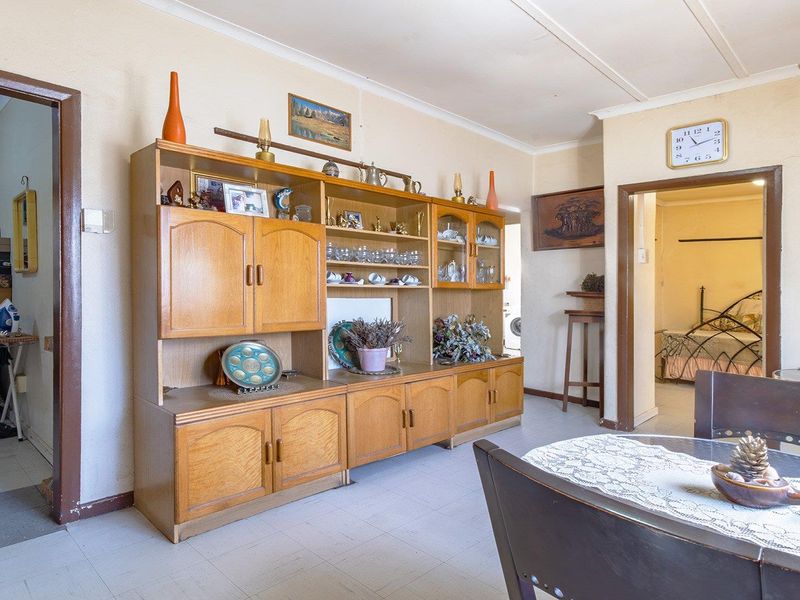 A living area featuring tiled flooring and coved ceilings, providing a functional space with potential for modernization.