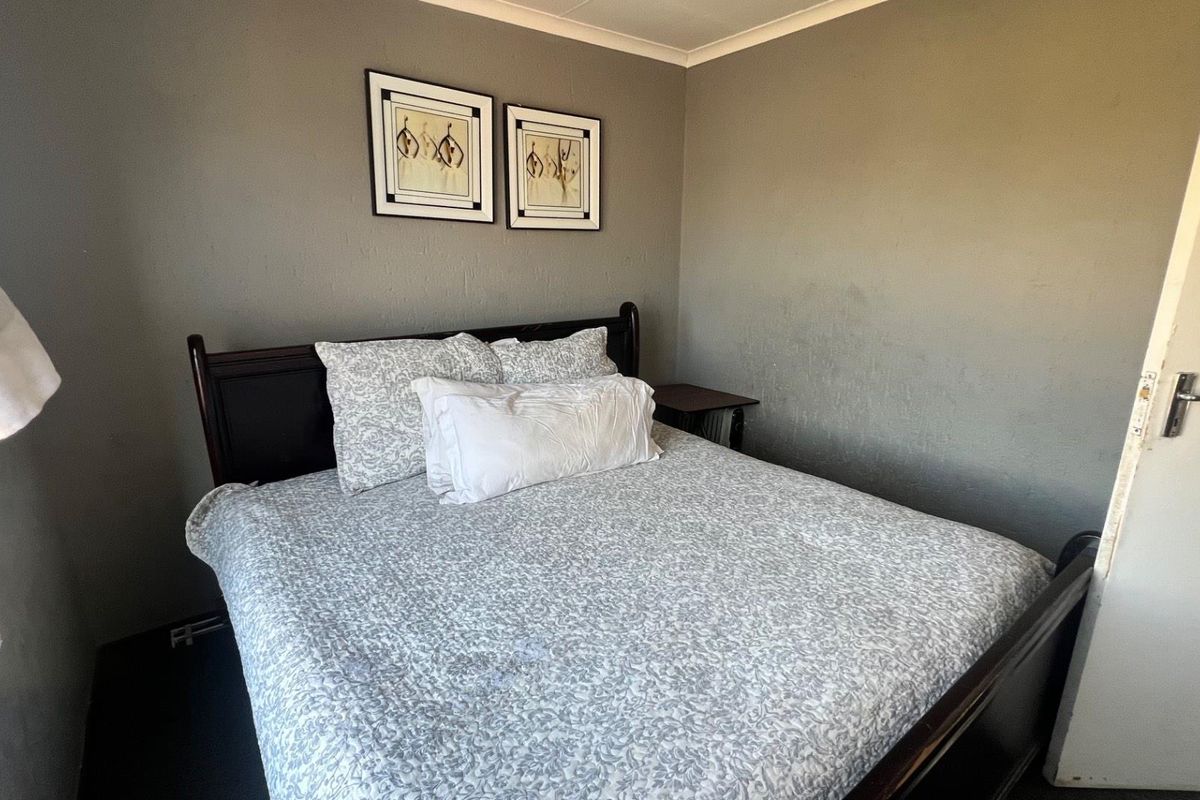 A standard bedroom featuring neutral grey walls and a built-in door frame, providing a functional and simple sleeping space.